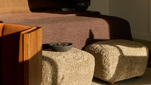 Modern bedroom with a bed, ottomans, and a lamp.