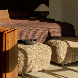 Modern bedroom with a bed, ottomans, and a lamp.